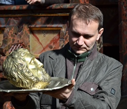 Fotografia Andrzeja Betleja trzymającego w dłoniach srebrną głowę św. Jana Chrzciciela na misie